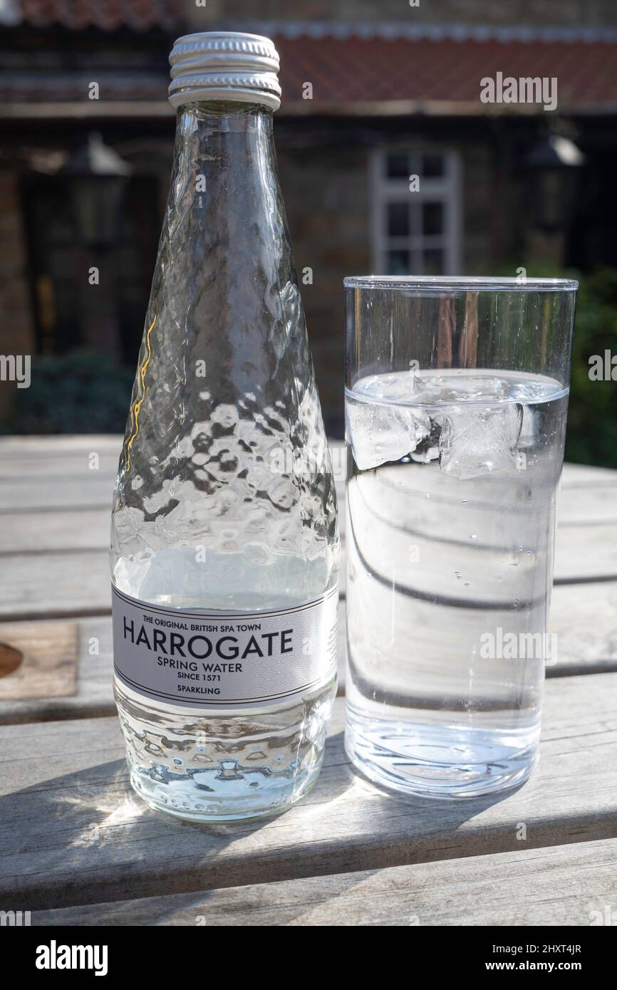Harrogate Spa Sparkling acqua minerale, l'originale British Spa Town Spring acqua dal 1571 bottiglia e bicchiere su un tavolo esterno Foto Stock