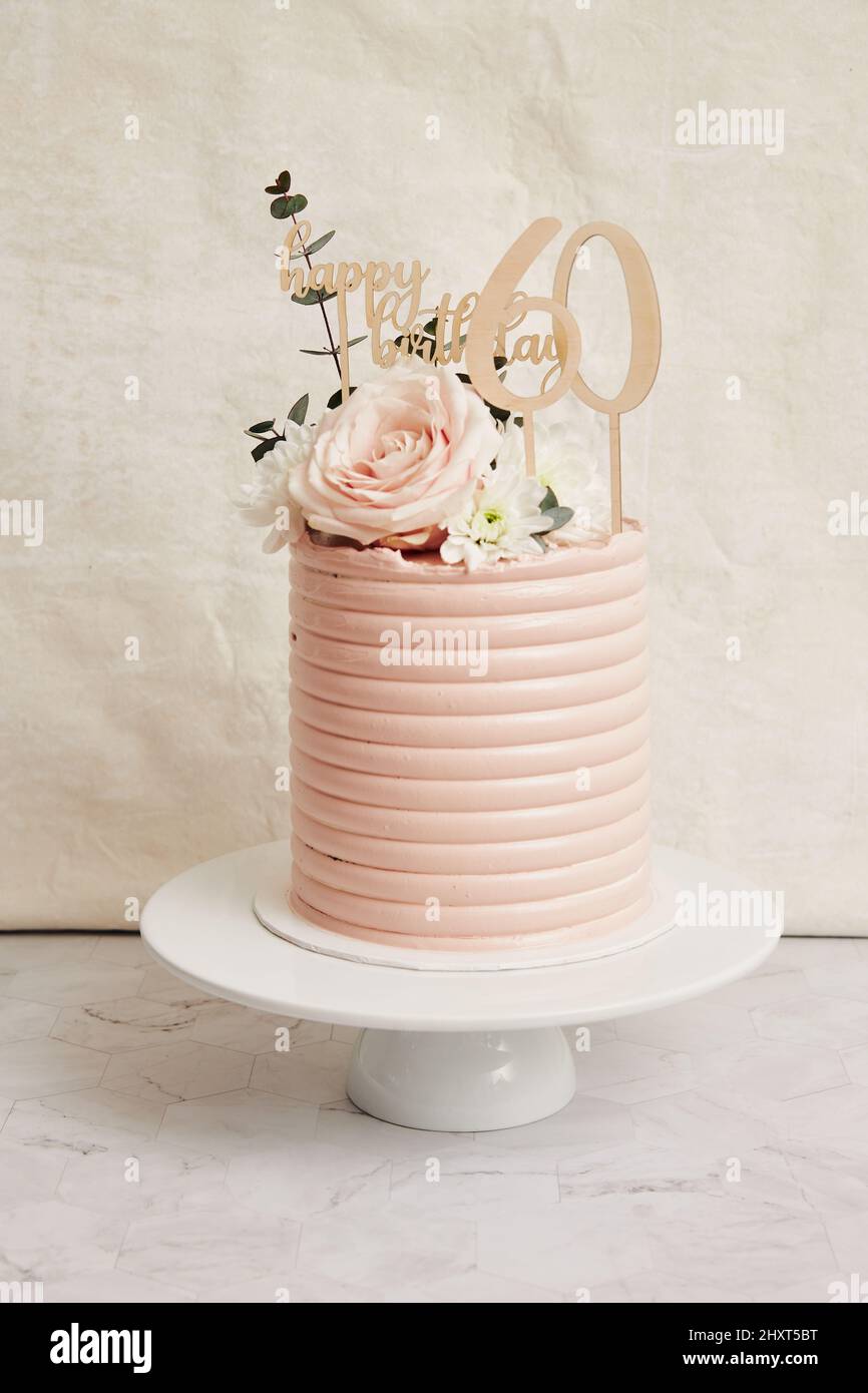 Primo piano verticale di una torta di compleanno di 60 anni su un supporto  per torte con glassa rosa chiaro Foto stock - Alamy