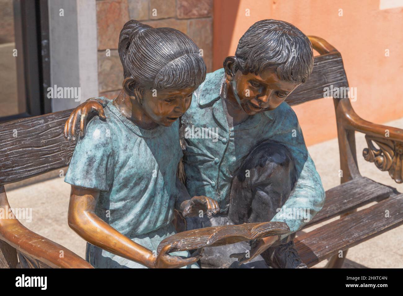 Foto di un monumento in bronzo di un ragazzo e una ragazza che legge sulla panchina in Thailandia Foto Stock