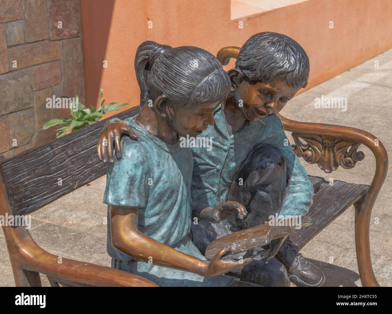 Foto di un monumento in bronzo di un ragazzo e una ragazza che legge sulla panchina in Thailandia Foto Stock