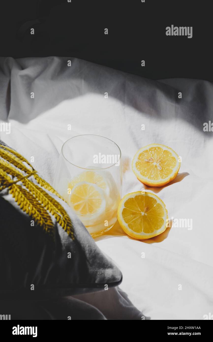 Rinfrescante succo di limone e due metà di limone sulla coperta bianca sotto la luce del sole Foto Stock