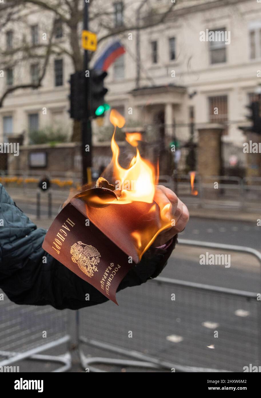 Un cittadino russo brucia il suo passaporto russo tra i manifestanti fuori dall'ambasciata russa a Londra per protestare contro la guerra Ucraina. Foto Stock