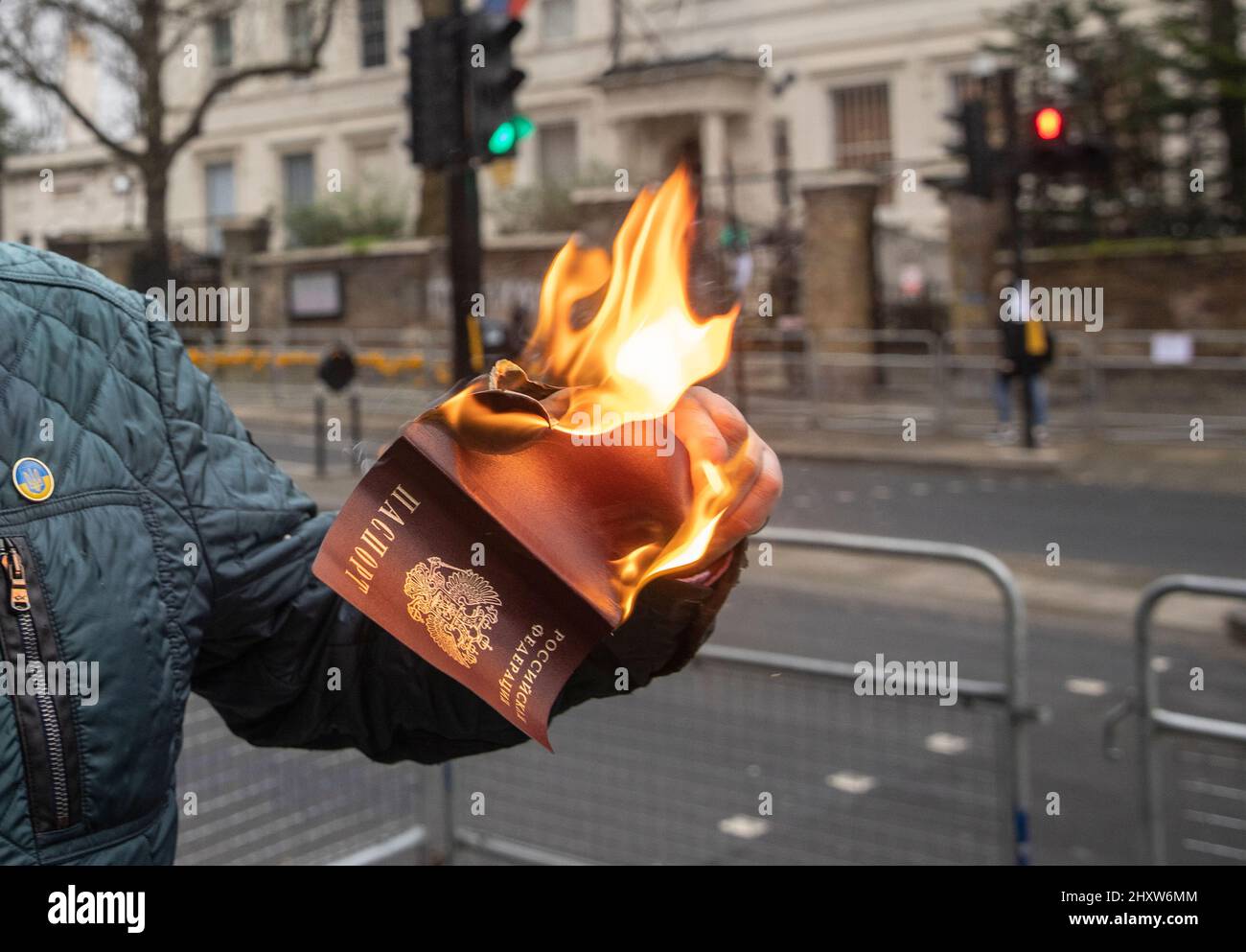 Un cittadino russo brucia il suo passaporto russo tra i manifestanti fuori dall'ambasciata russa a Londra per protestare contro la guerra Ucraina. Foto Stock