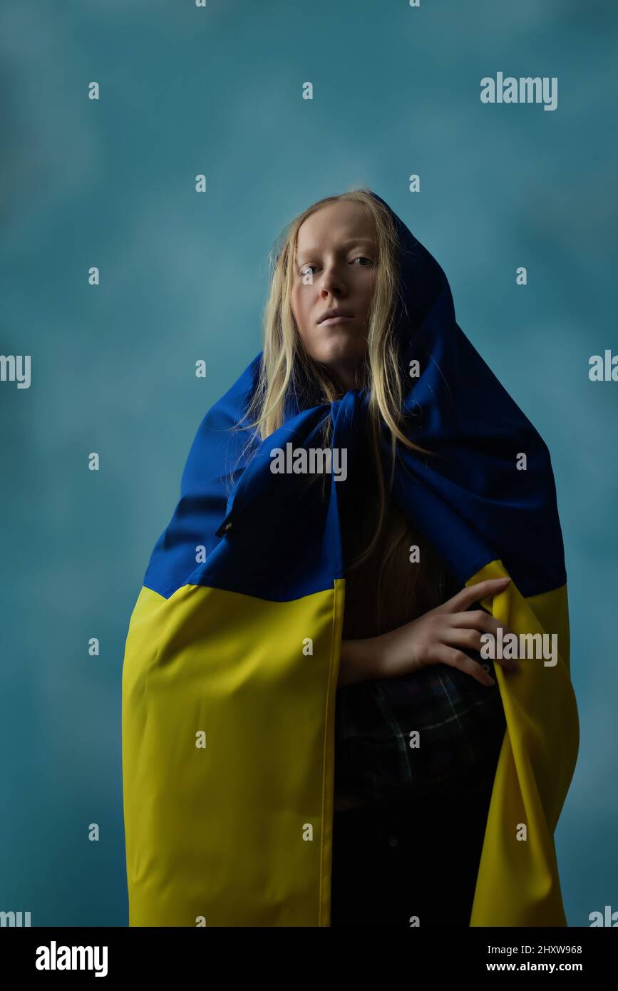 Una vera bionda Ucraina durante la guerra con la bandiera Ucraina gialla e blu sulla sua testa come un fazzoletto. La Russia ha attaccato l'Ucraina il 24 febbraio 2022. Foto Stock