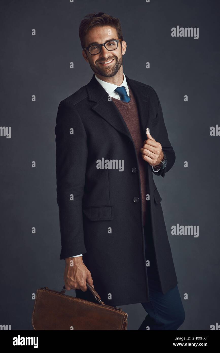 Vestire per l'uomo che sei. Ritratto da studio di un giovane uomo vestito con eleganza che porta una borsa su uno sfondo grigio. Foto Stock