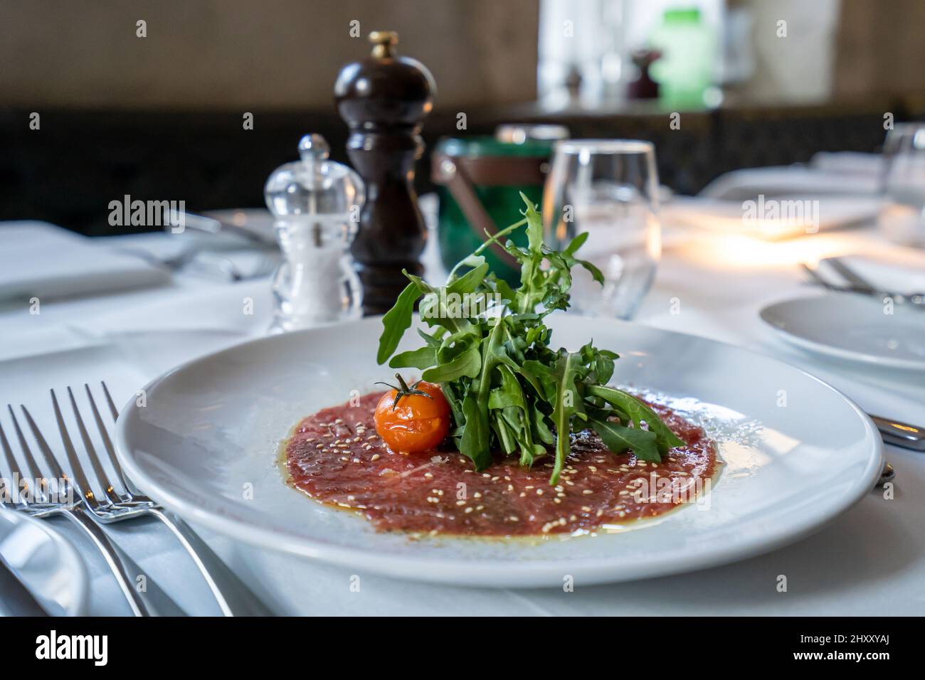 Carpaccio di manzo con rucola e pomodori su un piatto bianco in un  ristorante Foto stock - Alamy