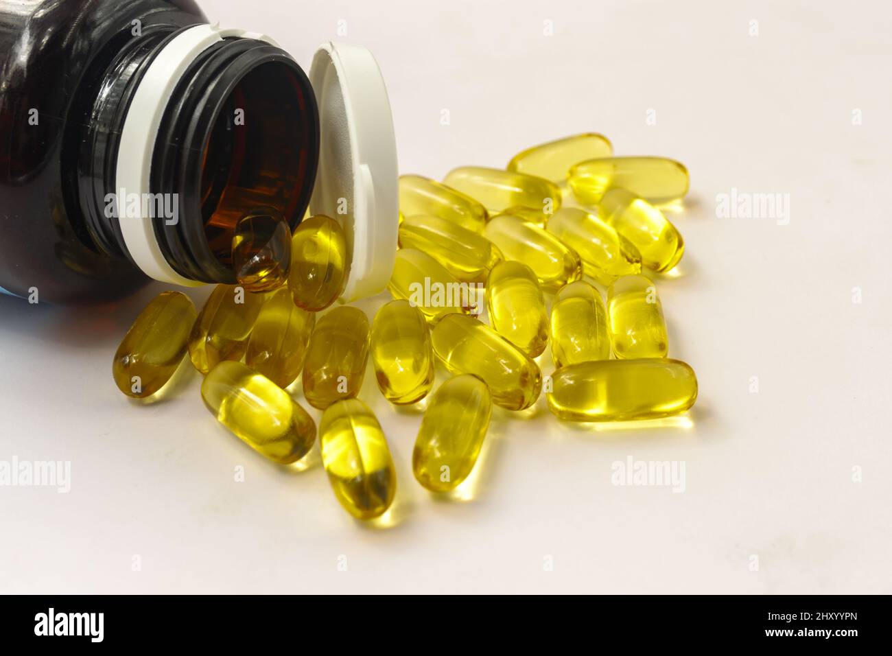 Primo piano della capsula gialla su sfondo bianco vicino a un vaso medico Foto Stock