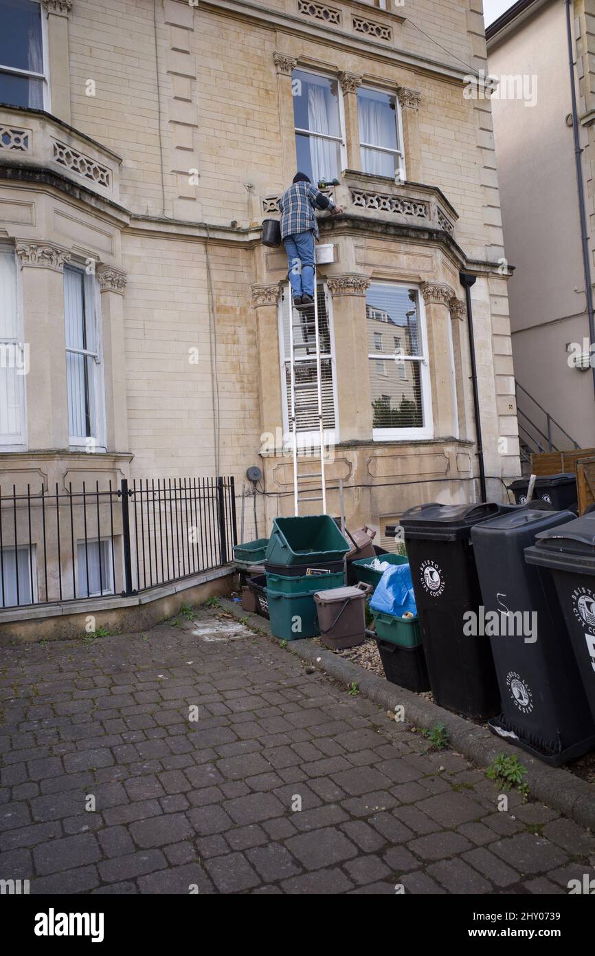 Marzo 2022 - Guy lavora da solo su una scala che fissa un edificio a Clifton, Bristol. Foto Stock