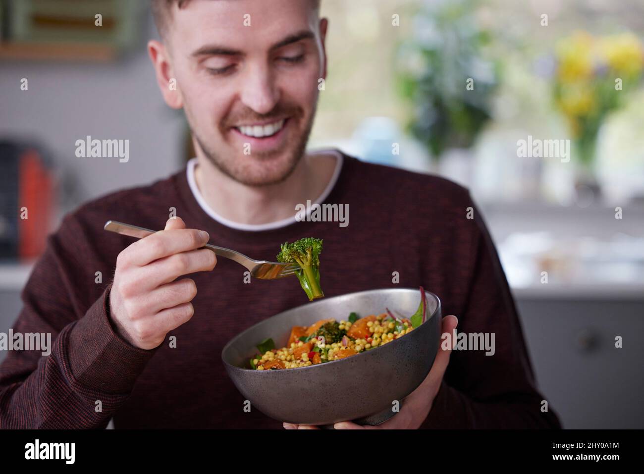 Primo piano dell'uomo mangiare sano Vegan pranzo in cucina a casa Foto Stock