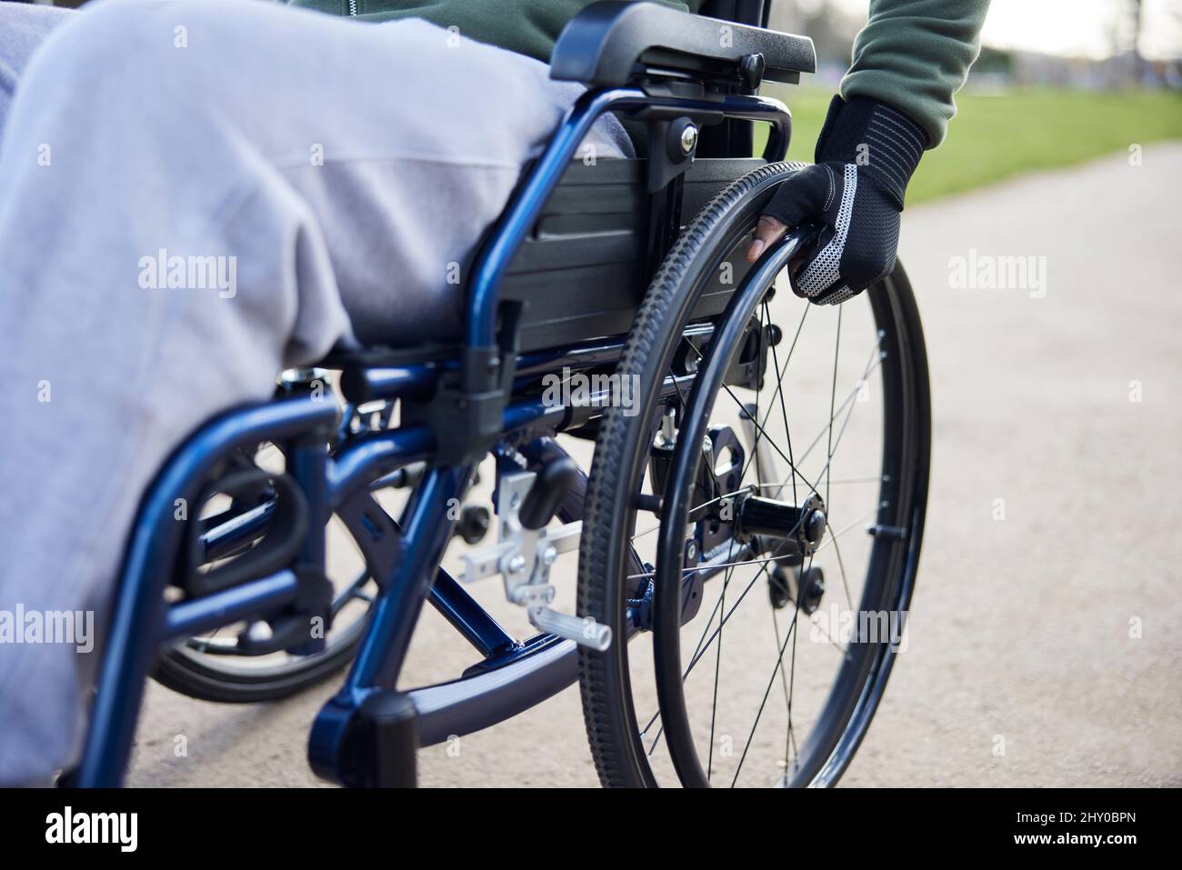 Primo piano di Teenage Boy indossando guanti protettivi in sedia a rotelle a Park Foto Stock
