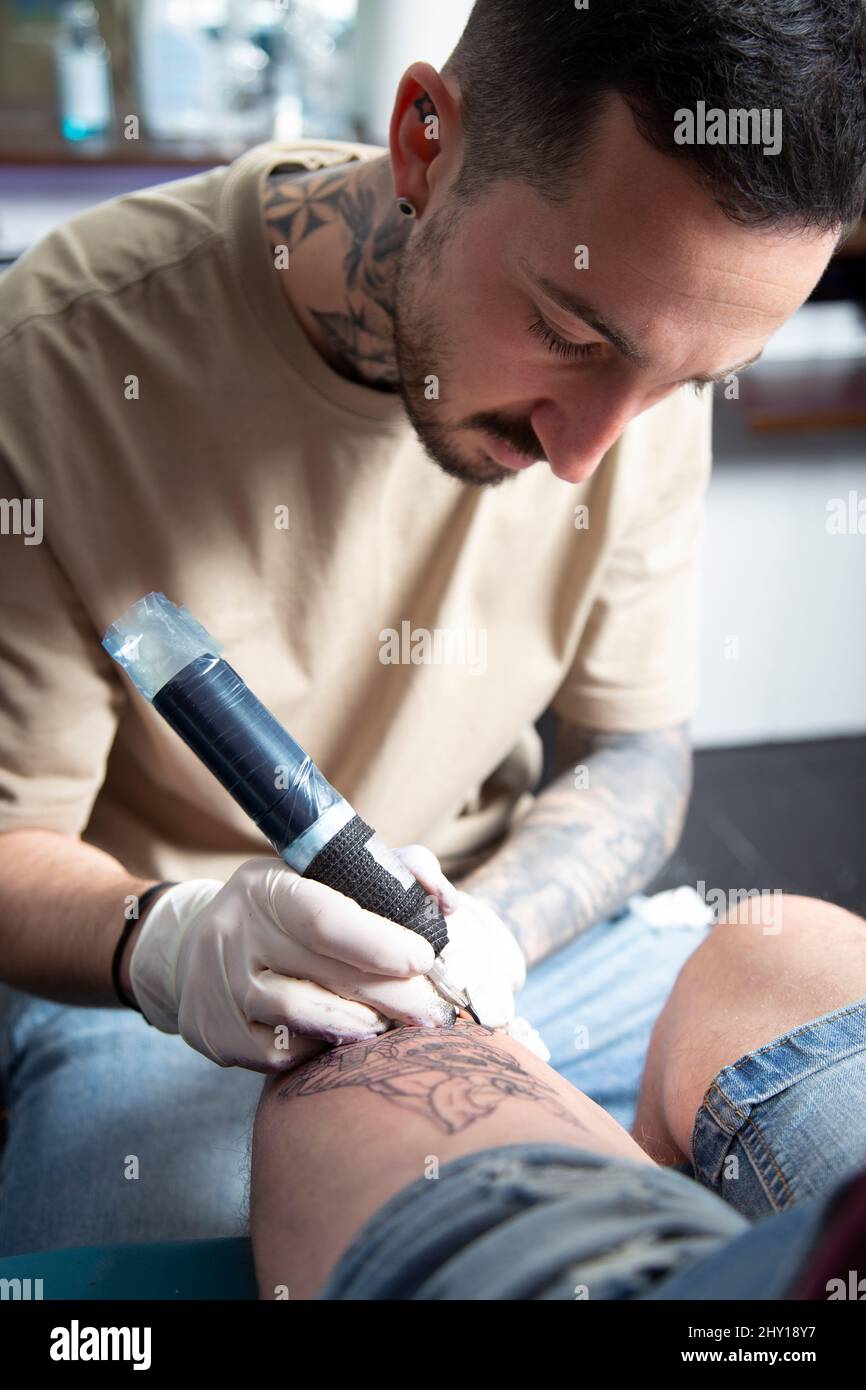 Tatuaggio professionale master in guanti in lattice facendo tatuaggio su  gamba di cliente anonimo con moderna macchina rotativa tatuaggio penna Foto  stock - Alamy