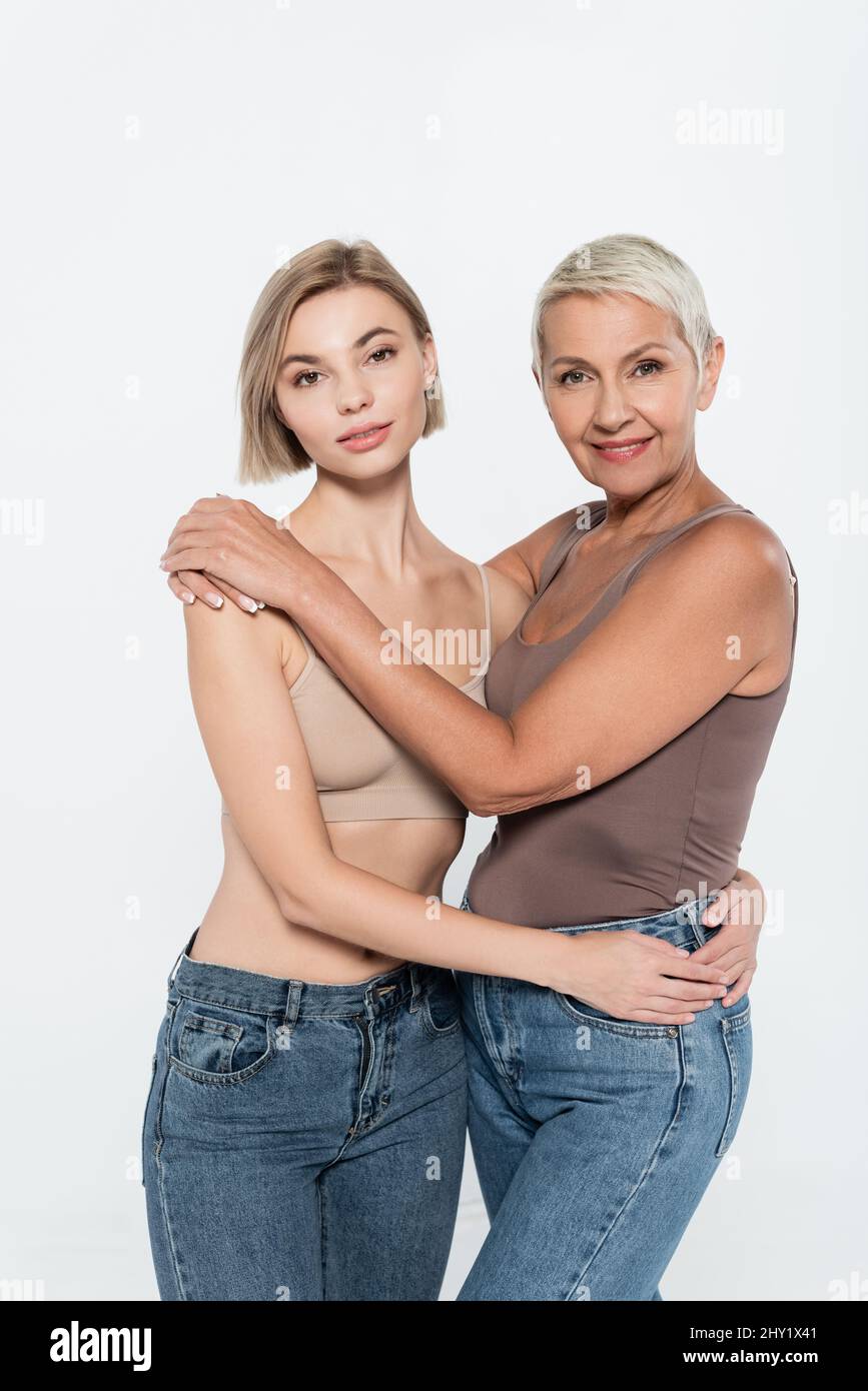 Donne in jeans abbracciano e guardando la fotocamera isolata su grigio, femminismo concetto, immagine stock Foto Stock