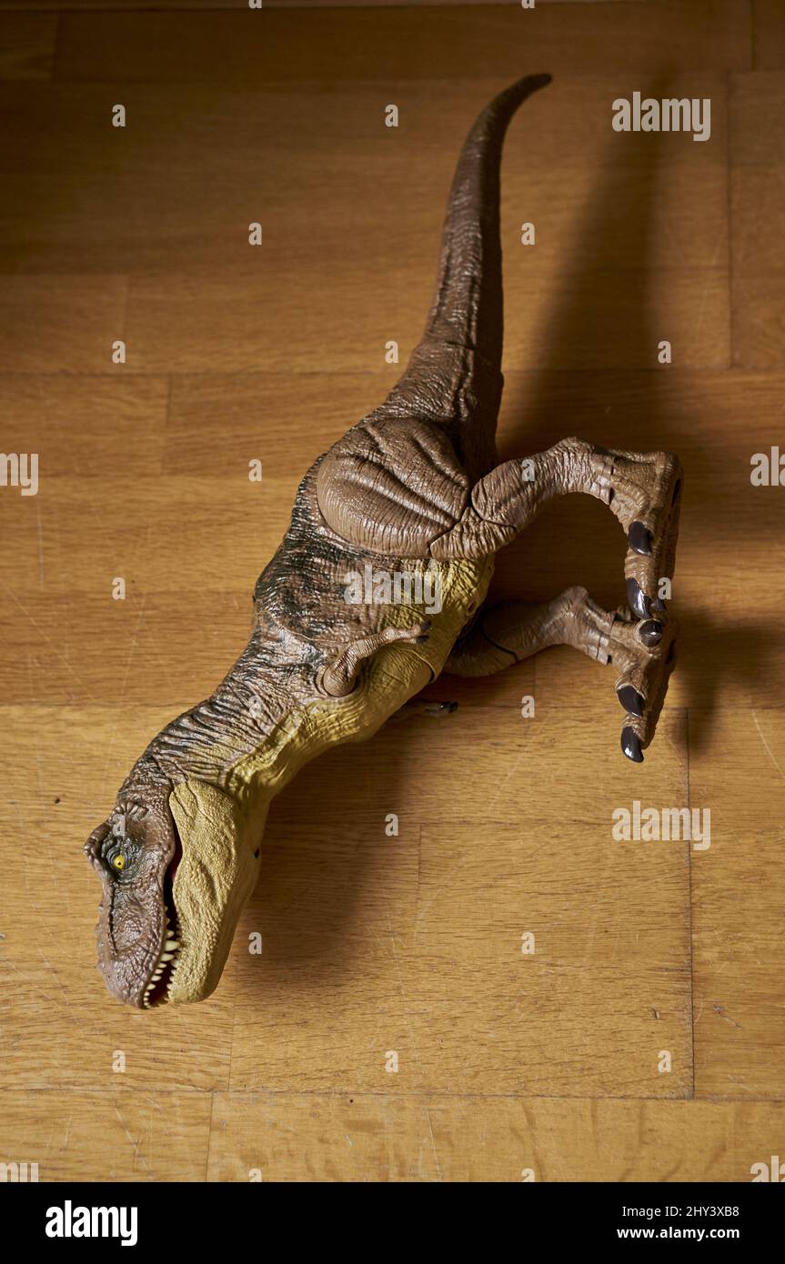 Primo piano verticale di Mattel Jurassic World personaggio giocattolo Tyrannosaurus Rex giacente su un pavimento in legno. Foto Stock