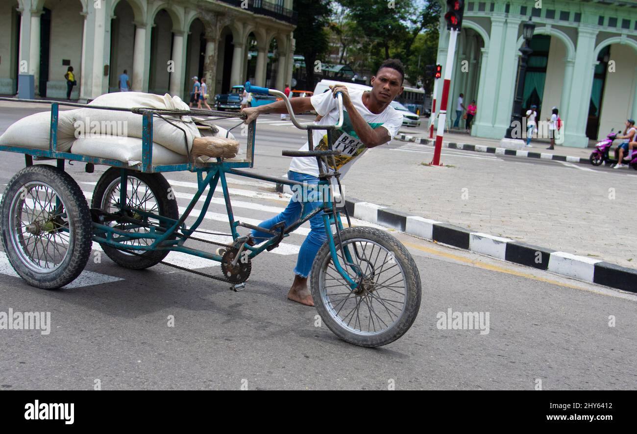Uomo cubano che spinge la bicicletta mentre lavora per le strade di l'Avana, Cuba. Foto Stock