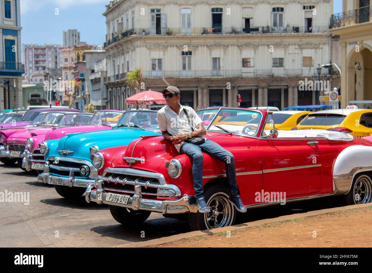 Uomo seduto sulla cima di un vecchio americano fatto auto su un angolo strada a Old Havana, Cuba. Foto Stock