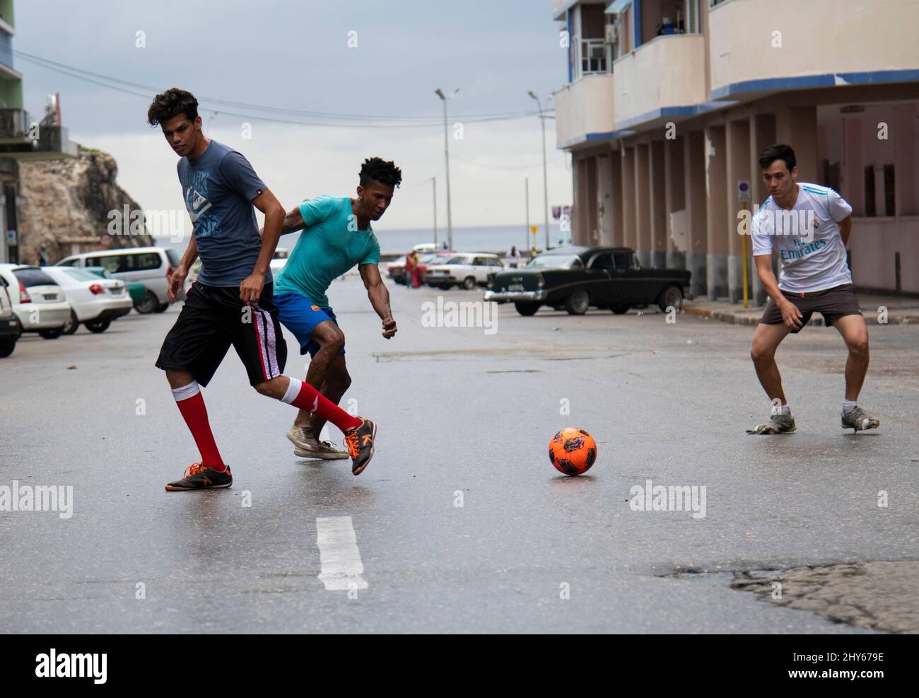 Giovani ragazzi che giocano a calcio nel mezzo di una strada trafficata a l'Avana, Cuba. Foto Stock