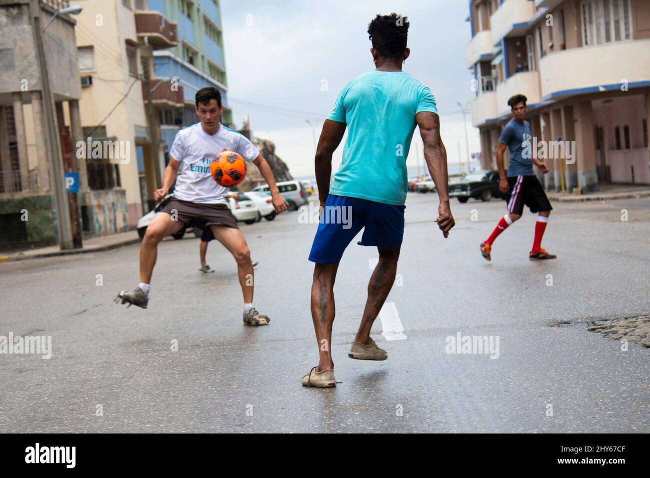Giovani ragazzi che giocano a calcio nel mezzo di una strada trafficata a l'Avana, Cuba. Foto Stock