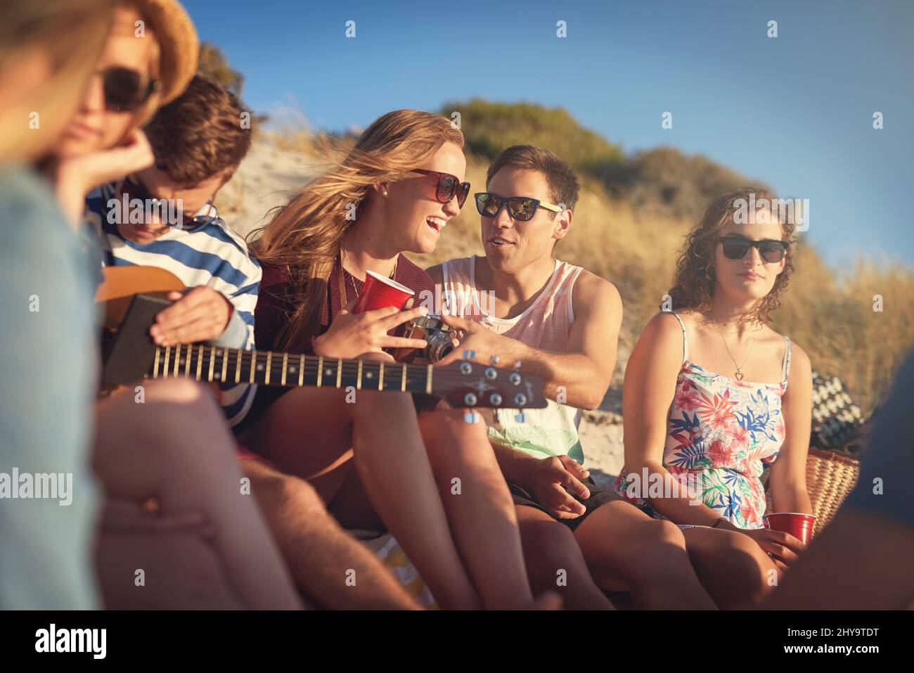 Le amicizie dolci portano delle risate dolci. Scatto corto di un gruppo di giovani amici appesi insieme in una giornata estiva in spiaggia. Foto Stock