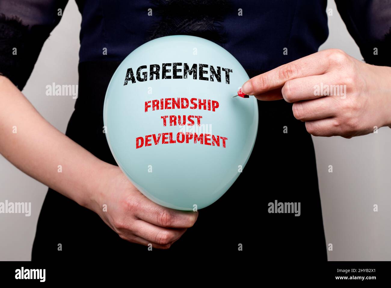 Accordo. Concetto di amicizia, fiducia e sviluppo. La donna esplode un palloncino con un ago. Foto Stock