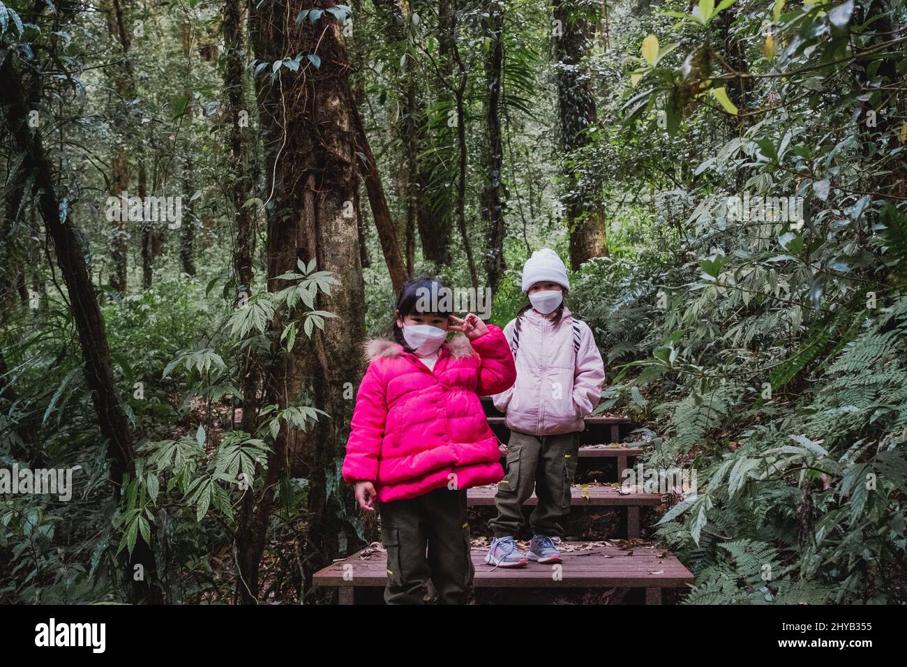 Bambini con zaini escursioni in natura con la famiglia. Due bambini in abiti invernali esplorano la foresta, giocano e imparano in natura. Una nuova normale li Foto Stock