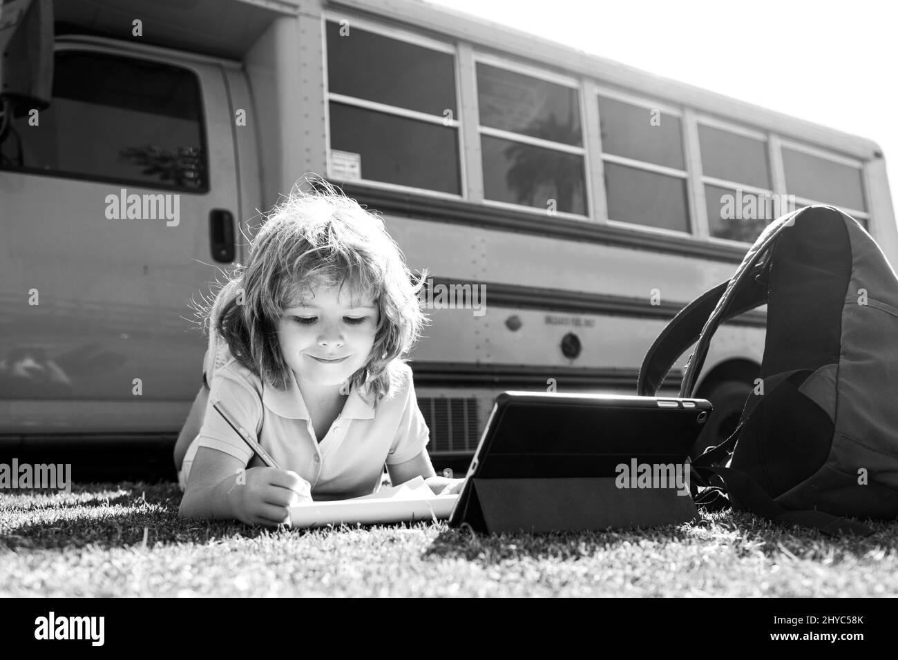 Ritorno a scuola. Felice bambino studio nel parco. Ragazzo della scuola che fa i compiti o l'istruzione in linea. Foto Stock