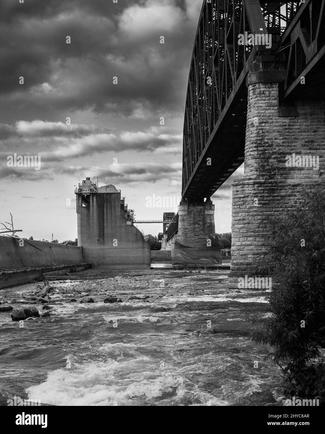 Un colpo verticale di ponte sul fiume con cielo nuvoloso sullo sfondo Foto Stock