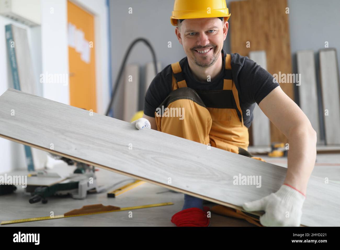 L'uomo qualificato del carpentiere trasporta la tavola di legno sul  progetto di lavoro, operaio energetico Foto stock - Alamy