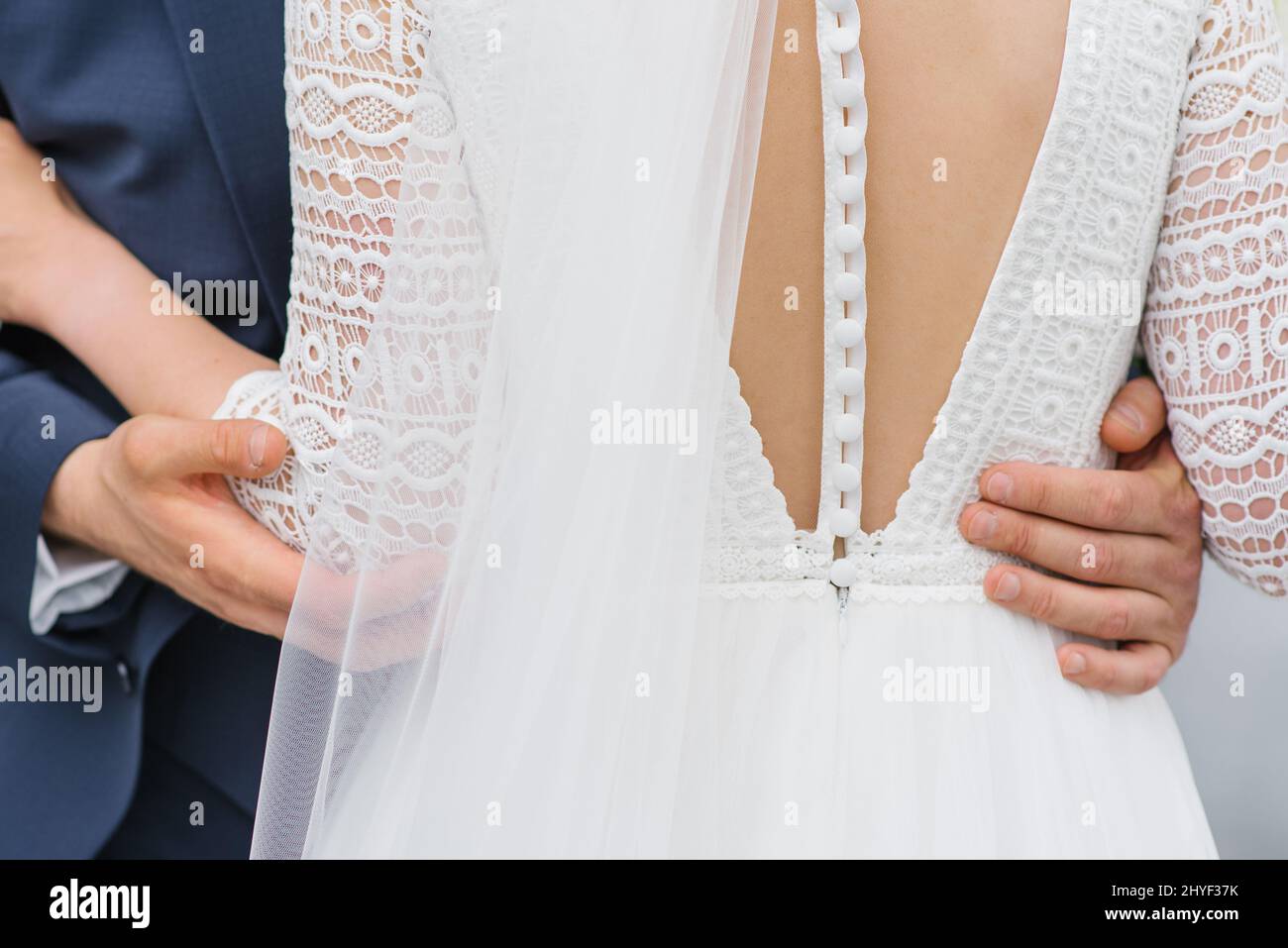 Bella bridesmaid vestire con numerosi pulsanti. Lo sposo abbraccia la vita della sposa, da vicino Foto Stock