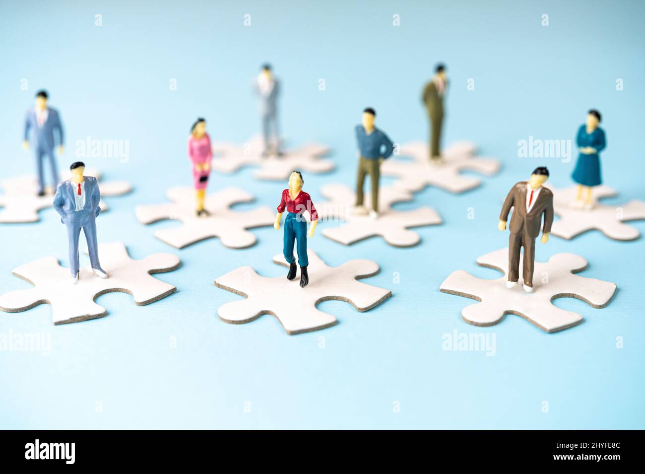 alcuni modelli in miniatura della gente su alcuni pezzi di puzzle vuoti Foto Stock