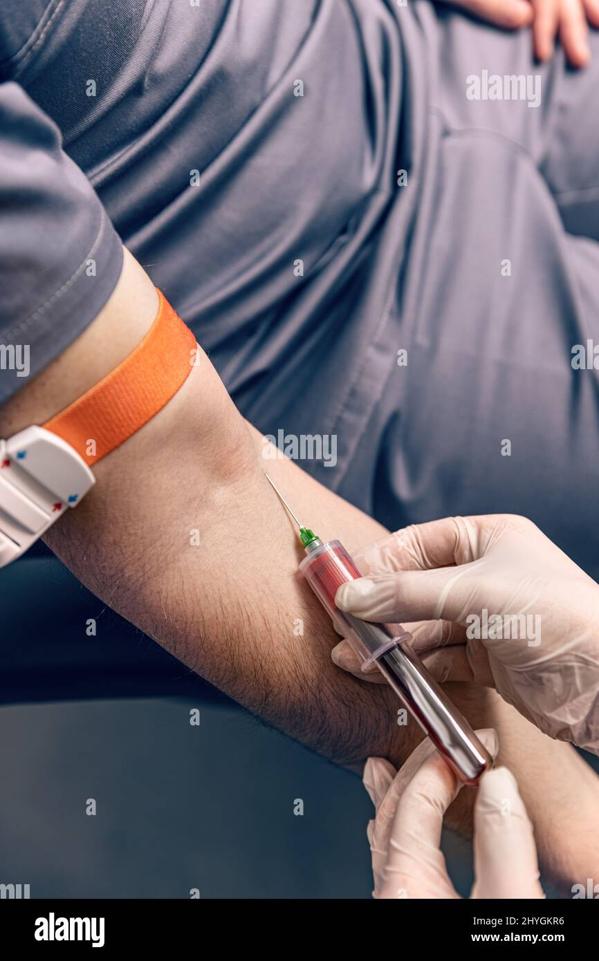 Infermiere che inietta il paziente maschio con la siringa per prelevare il campione di sangue Foto Stock