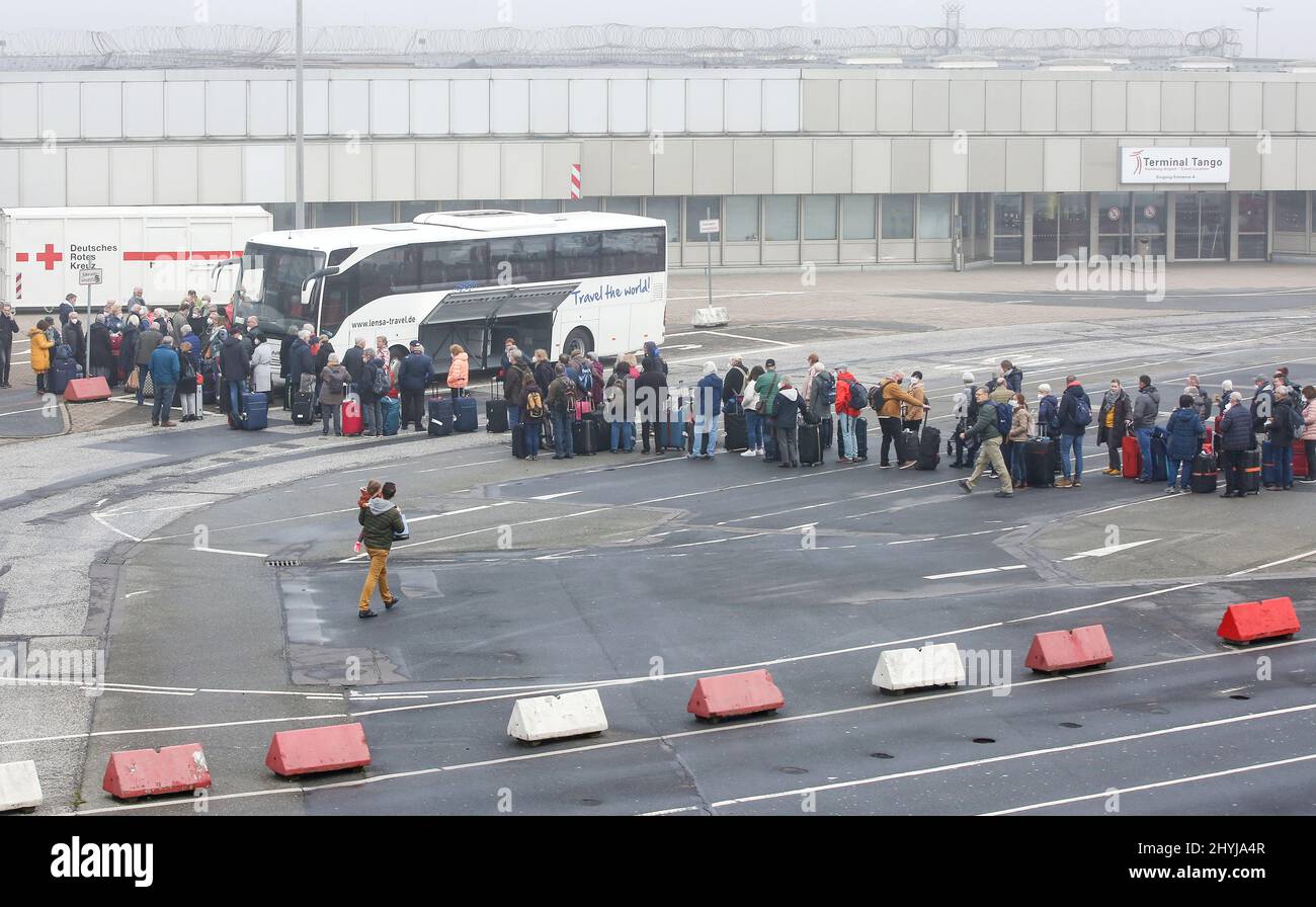 Amburgo, Germania. 15th Mar 2022. Numerosi viaggiatori d'aria si trovano in condizioni di nebbia all'aeroporto di fronte al terminal Tango, dove gli autobus sono pronti per il viaggio successivo. Secondo i viaggiatori, gli autobus devono viaggiare per l'aeroporto di Brema, tra gli altri luoghi. I passeggeri devono aspettarsi oggi cancellazioni e ritardi dei voli. Il sindacato Verdi ha invitato il personale di sicurezza che controlla i passeggeri ad Amburgo a fare un monito per un giorno. Credit: Bodo Marks/dpa/Alamy Live News Foto Stock