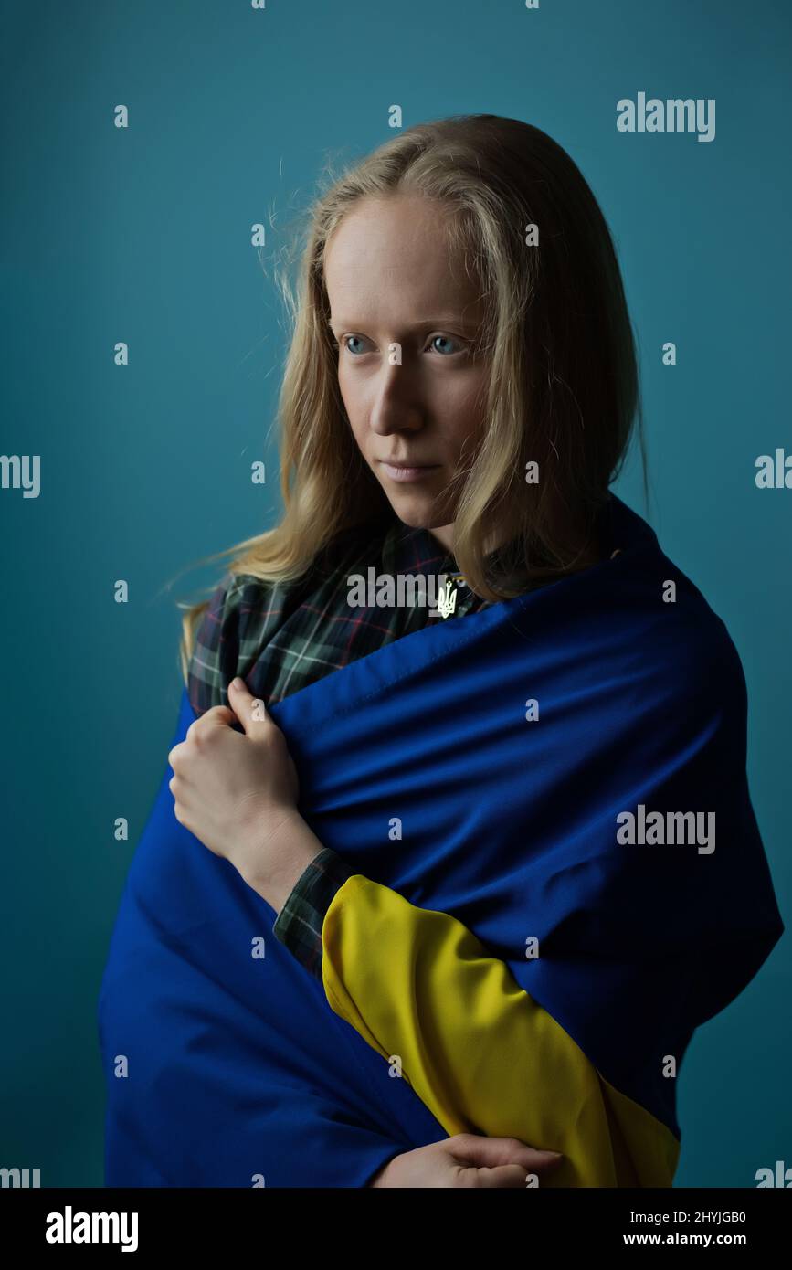 Una vera donna bionda Ucraina durante la guerra con la bandiera Ucraina gialla e blu sulla sua testa. La Russia ha attaccato l'Ucraina il 24 febbraio 2022. Foto Stock