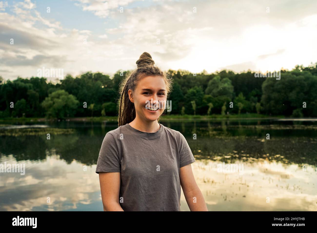 Portait di donna sorridente con prechi nel parco, sfondo lago. Foto Stock