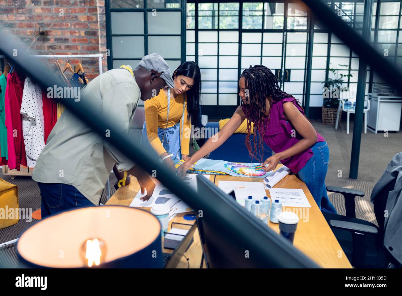 Multirazziale giovane fashion designer maschile e femminile che discute sui disegni alla scrivania Foto Stock