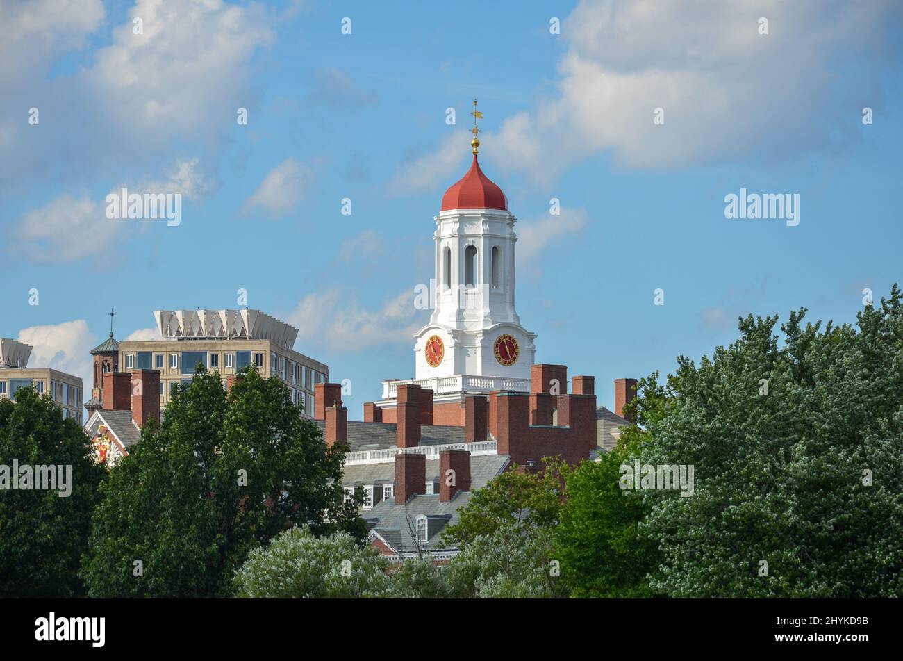 Boston, USA - Agosto 3 2013: Vista attraverso gli alberi fino alla Harvard University Dunster House con il suo tetto a cupola rosso e l'orologio rosso della torre Foto Stock