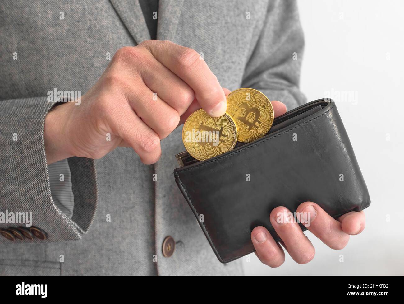 Uomo d'affari che indossa un vestito, che tiene un portafoglio e Bitcoin BTC cripto monete d'oro, nuovo concetto di denaro virtuale. Tecnologia mineraria o blockchain Foto Stock
