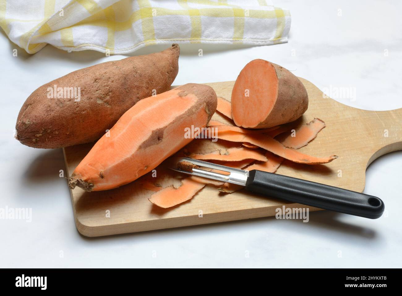 Patate dolci (Ipomoea batatatatas), patate dolci sbucciate con pelapatate Foto Stock