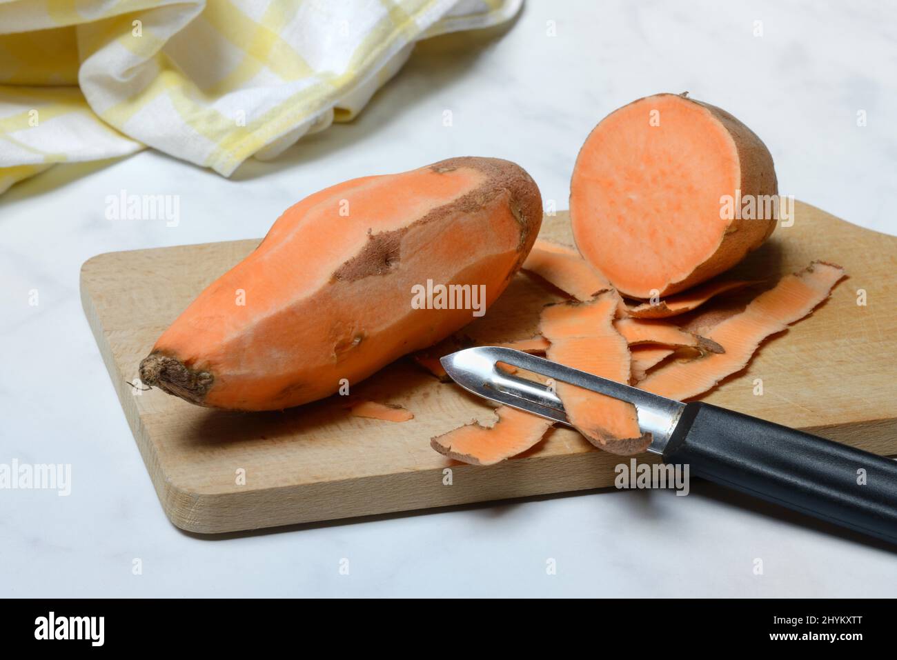 Patate dolci (Ipomoea batatatatas), patate dolci sbucciate con pelapatate Foto Stock