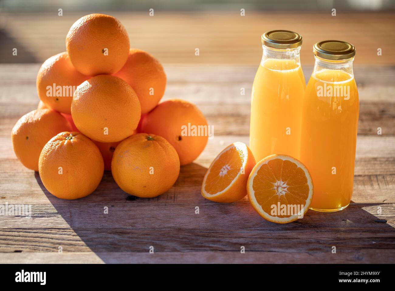 Succo d'arancia, biologico, fatto in casa, spremuto di fresco in bottiglia accanto alle arance al sole del mattino Foto Stock