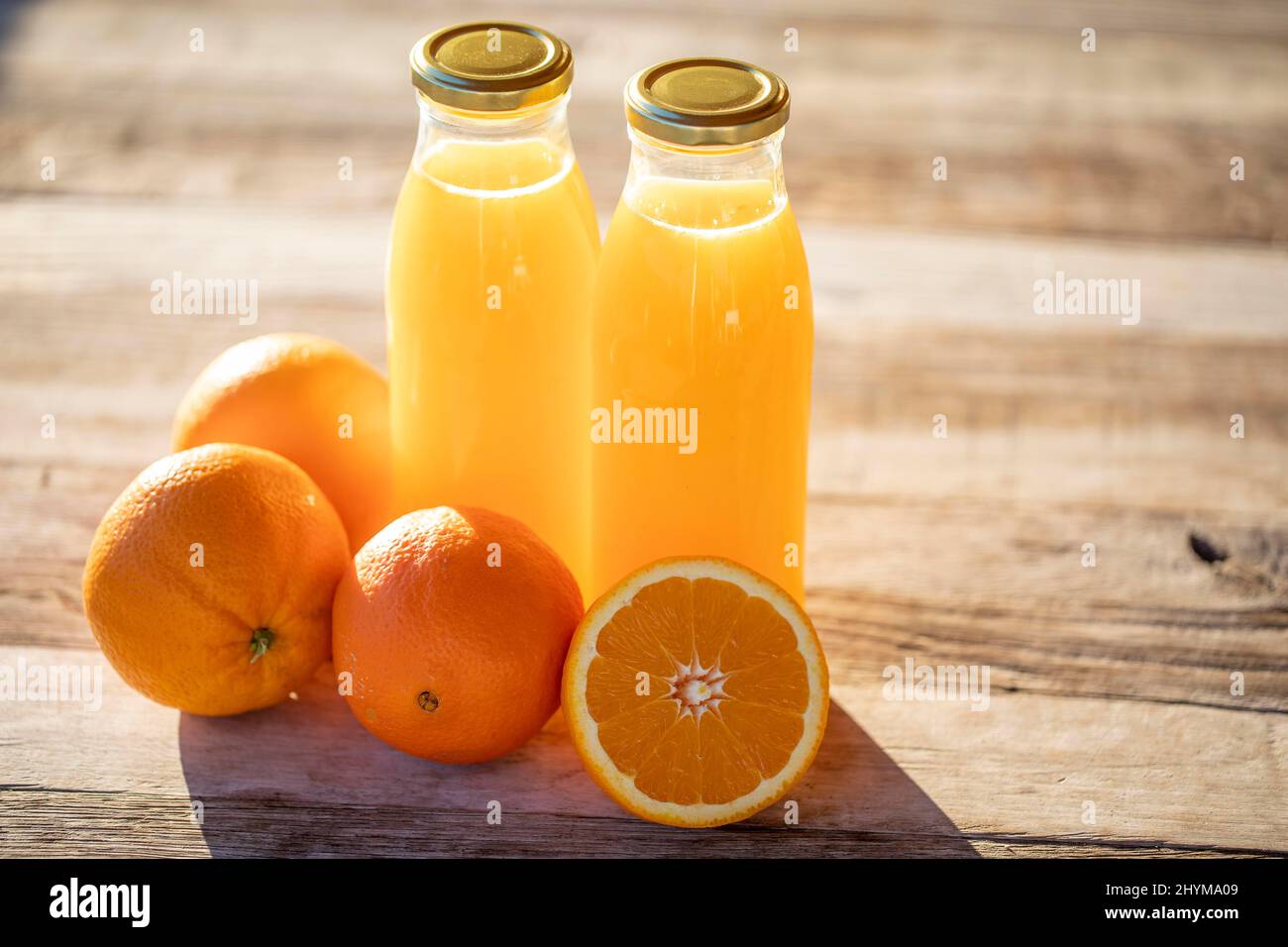 Succo d'arancia, biologico, fatto in casa, spremuto di fresco in bottiglia accanto alle arance al sole del mattino Foto Stock