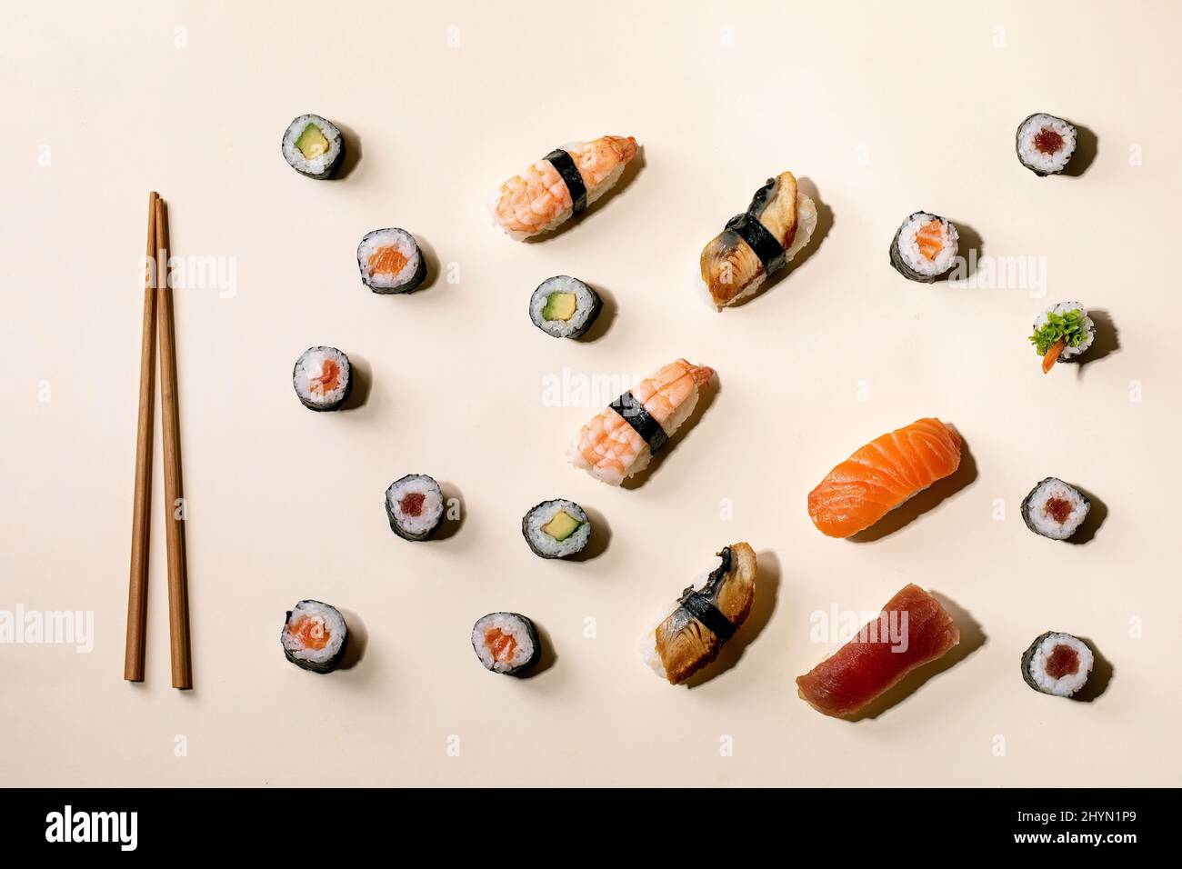 Set di sushi roll. Sushi tradizionale giapponese e panini con salmone fresco, tonno, anguilla e gamberi su riso, chopsics di legno su sfondo beige con Foto Stock