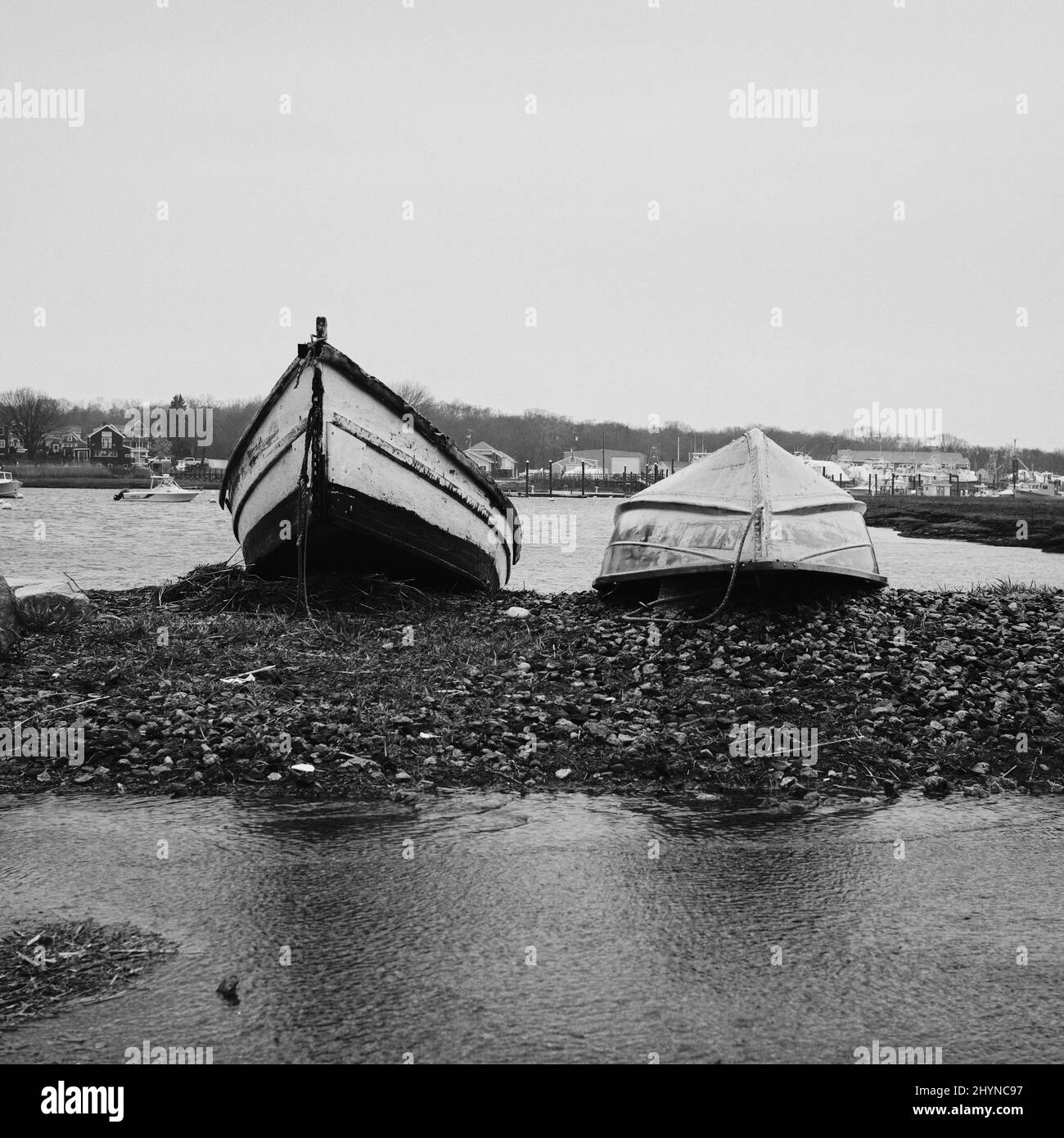 Foto in scala di grigi di vecchie barche da pesca sulla riva del lago Foto Stock