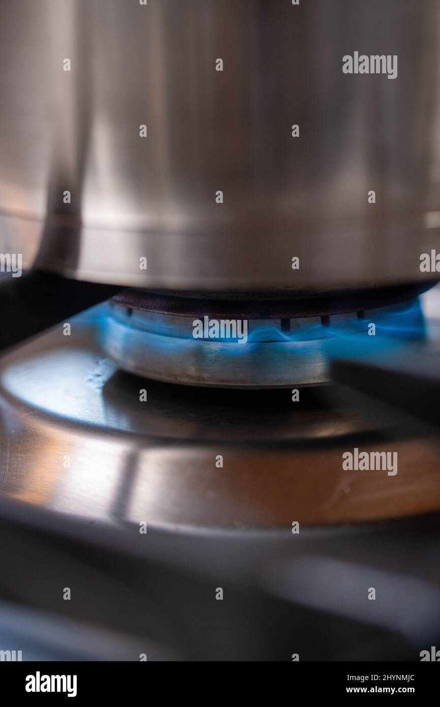 Primo piano di gas che brucia sotto una pentola di cottura su una stufa in cucina. Foto Stock