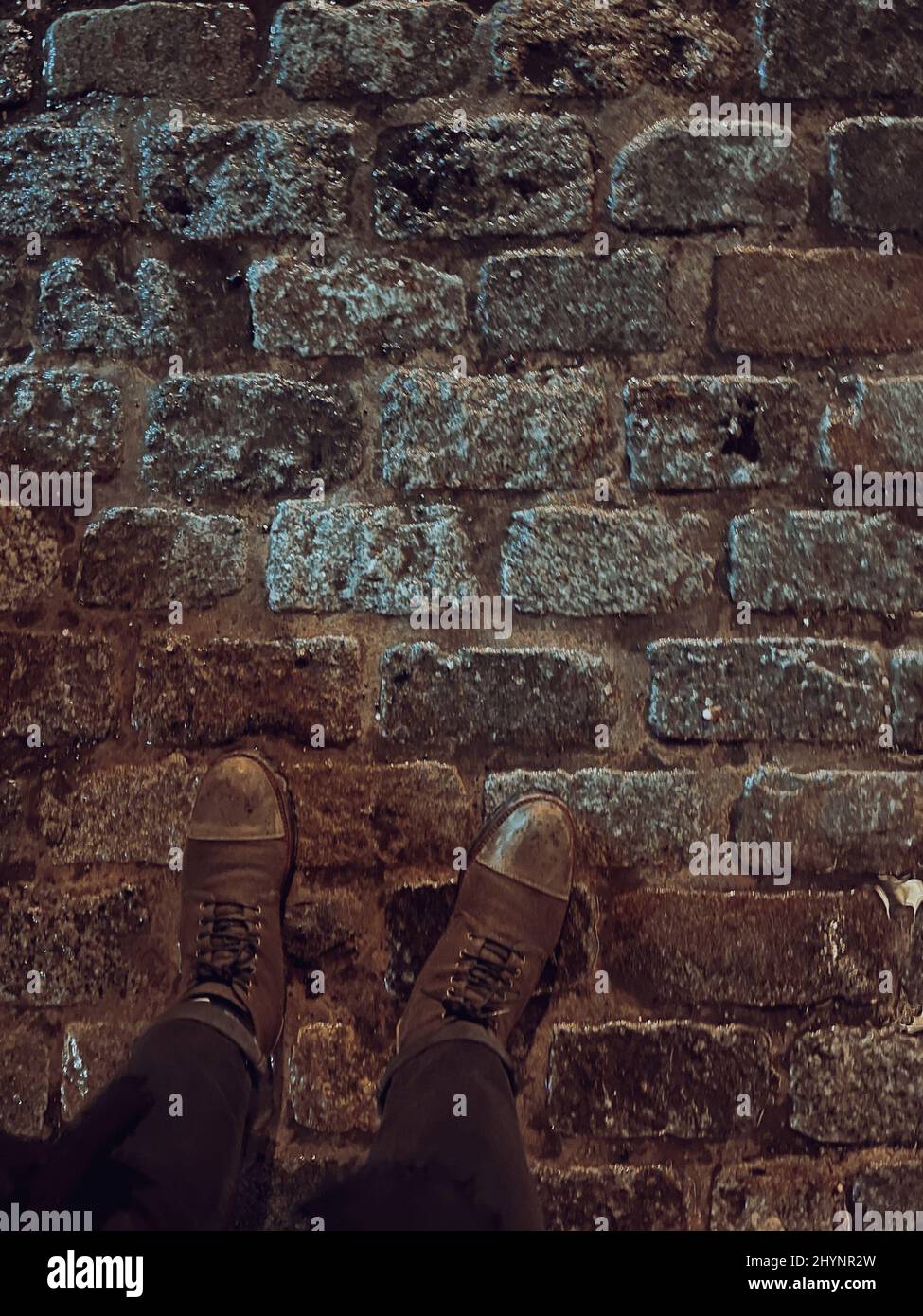 Vista dall'alto dei piedi su un terreno in pietra di mattoni Foto Stock