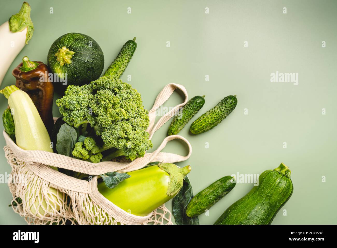Borsa a rete ecologica con verdure biologiche verdi su sfondo verde. Disposizione piatta, vista dall'alto. Concetto senza rifiuti, senza plastica. Dieta sana, pulita e disintossicante Foto Stock