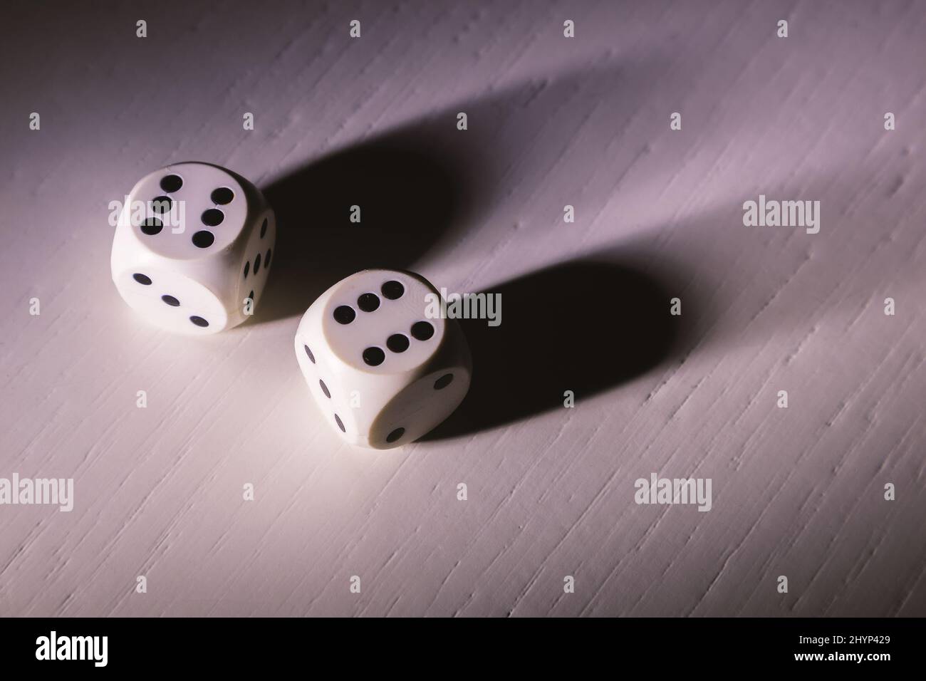 Dettagli dei cubi da gioco su un tavolo di legno bianco, illuminati da parte, dettagli d'ombra dura. Foto Stock