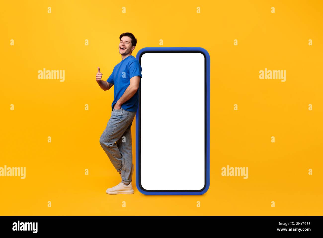 Ragazzo appoggiato sullo schermo bianco dello smartphone che mostra i pollici verso l'alto Foto Stock