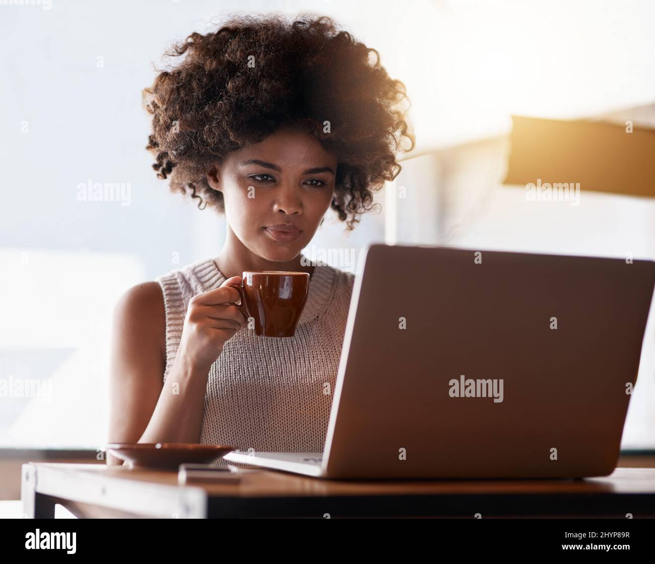 Shes vivere la cultura del caffè. Scatto di un giovane proprietario di affari usando un laptop mentre si siede nel suo caffè. Foto Stock