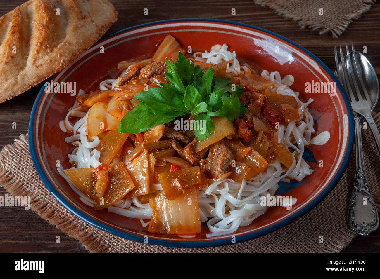 Piatto Uighur caldo servito con erbe e pane piatto. Foto Stock