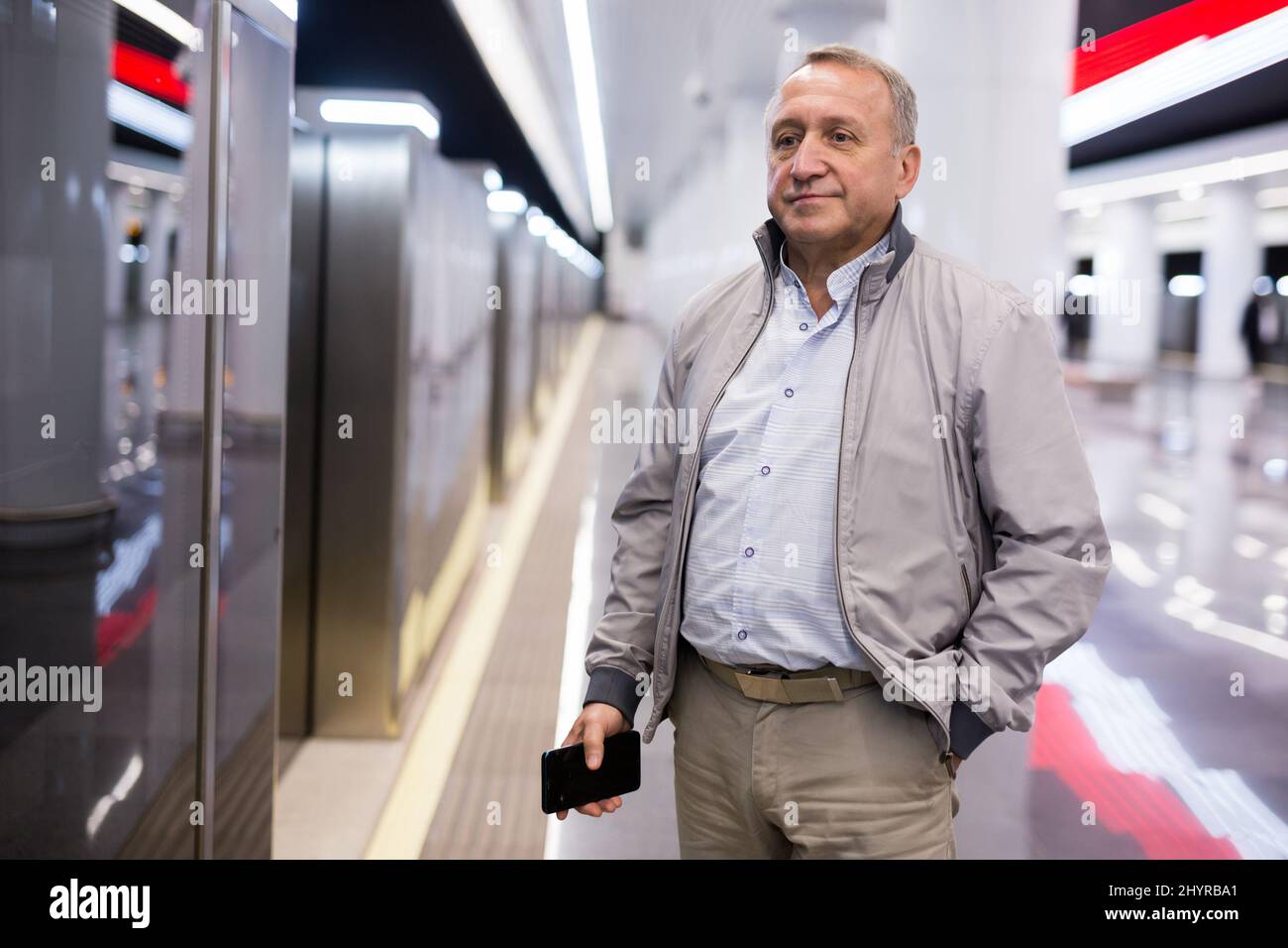 Uomo di mezza età in attesa di treno alla stazione della metropolitana Foto Stock